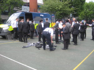 Students and police officers mingle around a police carrier.