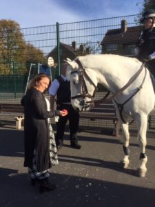 A teacher pets a mounted police horse.